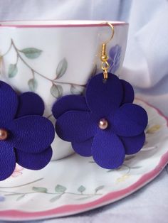 purple flower earrings on a tea cup