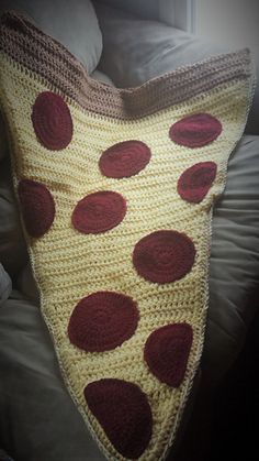 a crocheted pizza pillow is sitting on a bed