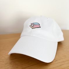 Our new Bookstack Hat is slightly heavier weight than the standard dad hat. It's made of 100% washed cotton twill and features multicolored embroidered thread. Features: 100% washed cotton twill 6-panels, unstructured and low profile Sewn Eyelets Self Fabric closure with D-ring slider and tuck-in strap Cotton Dad Hat With Embroidered Logo, 5-panel Cotton Hat With Embroidered Logo, White Cotton 5-panel Dad Hat, White 5-panel Cotton Dad Hat, Cotton Baseball Cap With Embroidered Curved Visor, White Cotton Snapback Hat With Curved Brim, White Cotton Snapback Hat For Streetwear, Cotton Dad Cap, One Size Fits Most, Cotton Dad Hat