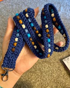 a hand holding two blue crocheted bracelets with beads on each side and a pair of scissors in the middle