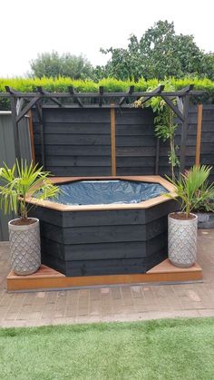 an outdoor hot tub surrounded by potted plants and wooden fence in the back yard