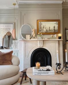 a living room filled with furniture and a fire place in front of a mirror on the wall