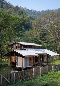 a small wooden house sitting on top of a lush green field next to a forest