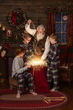 a man and two boys sitting in front of a christmas tree with a santa clause on it