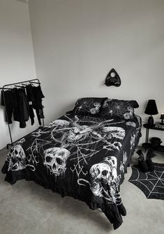 a black and white bedroom with skulls on the bedspread, clothes hanging up