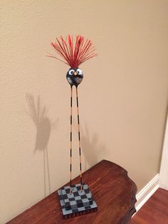 a wooden table topped with a black and white checkerboard vase filled with red hair