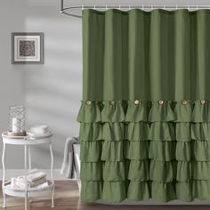 a green shower curtain with ruffled edges and gold buttons on the bottom tiers