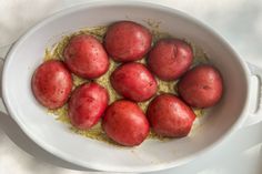 a white bowl filled with red potatoes on top of a table