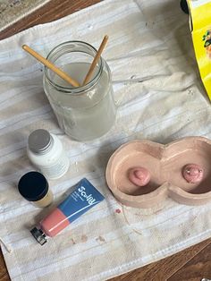 the contents of a makeup set on a towel next to an empty jar and toothbrush