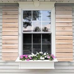 a window with shutters and flowers in the window sill on top of it