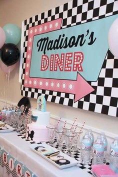 a table topped with lots of desserts and balloons in front of a sign that says madison's diner