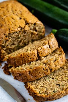 slices of zucchini bread sitting on top of a cutting board next to cucumbers