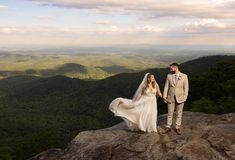 a bride and groom standing on top of a mountain