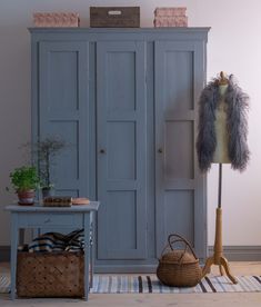 a blue armoire sitting next to a wooden table with a basket on top of it