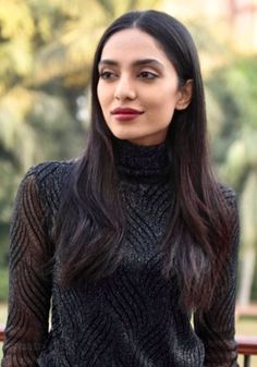 a woman with long dark hair wearing a black turtle neck sweater