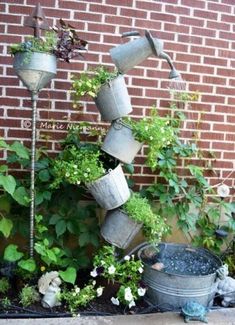 several pots are stacked on top of each other in front of a brick wall with plants growing out of them