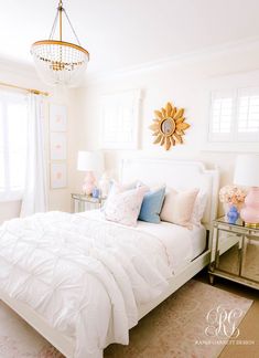 a white bed sitting in a bedroom next to a window and a chandelier