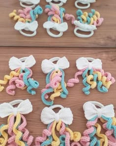 several crocheted bows are laid out on a wooden surface, one is white and the other is pink