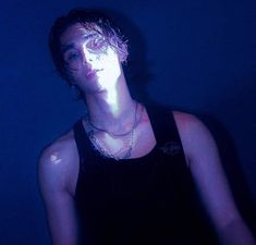 a young man wearing a black tank top in the dark with his face glowing brightly