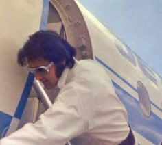 two men standing next to each other in front of an airplane door with sunglasses on