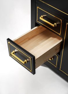 a black and gold dresser with two drawers on it's sides, one drawer open