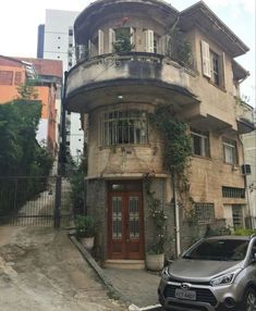 a car is parked in front of an old building with ivy growing on the windows