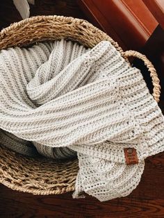 a basket filled with white blankets on top of a wooden floor