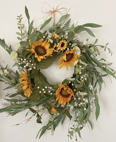 a wreath with sunflowers and greenery hanging on the wall