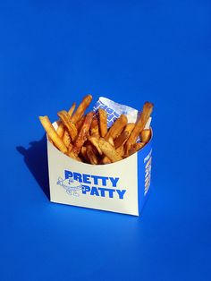 french fries in a paper box on a blue background with the words pretty patty written on it