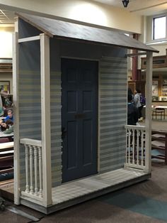 a small house made out of pallet boards in a building with people working on it