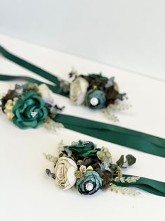 two flower bouquets with green ribbons on white surface