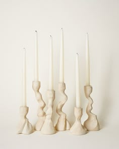 four white candles are lined up next to each other with one candle in the middle