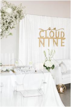 a table with white flowers and candles in front of a backdrop that says cloud nine