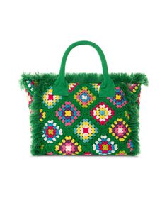 a green handbag with flowers and fringes on the front, sitting against a white background