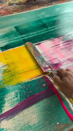 a person painting on a wooden table with colorful paint