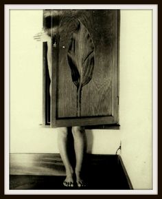 a woman standing in front of a wooden cabinet with a flower on it's side