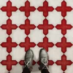 a person standing in front of a red and white tile floor with shoes on it