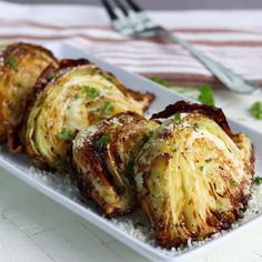 grilled artichokes with parmesan cheese and herbs on a white plate