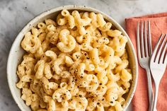 two bowls filled with macaroni and cheese on top of a marble countertop