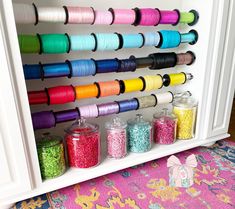 an organized craft closet filled with spools of thread and other colorful beads on the shelves