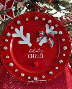 a red plate decorated with white reindeer antlers and the words holiday cheer on it