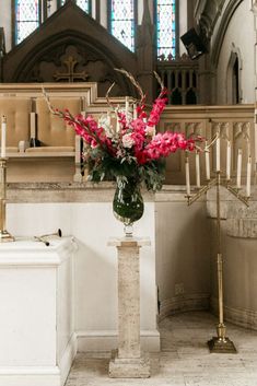 a vase filled with pink flowers sitting on top of a white table in front of a church