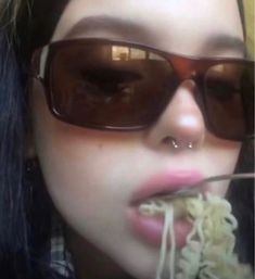 a woman wearing sunglasses and eating noodles