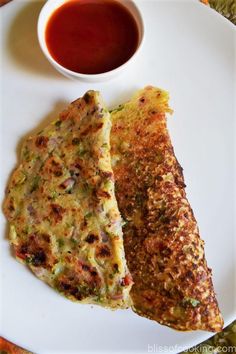 two pieces of omelet on a white plate with dipping sauce