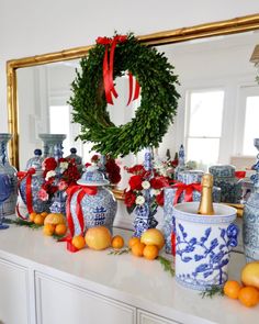 a decorated mantle with oranges, blue and white vases and wreath on it