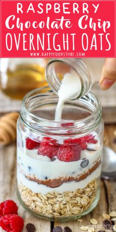 a person pouring milk into a jar filled with granola and raspberries