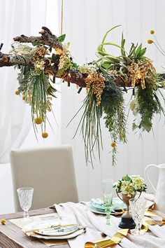 the table is set with flowers and greenery hanging from it's branches, along with other decorations