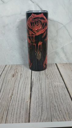 a black and red cup sitting on top of a wooden table next to a white wall