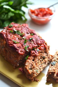 meatloaf with sauce and herbs on a yellow cutting board