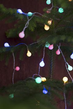 the christmas tree is decorated with multicolored balls and lights hanging from it's branches